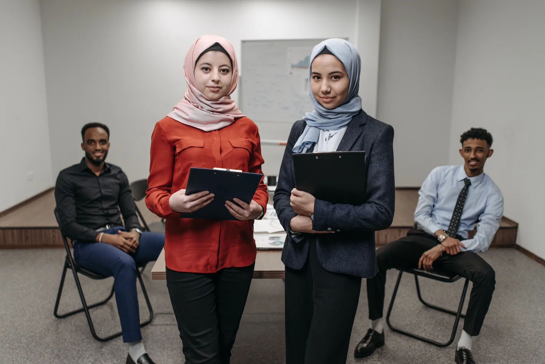Tim profesional dengan perempuan berhijab berdiskusi di ruang kerja