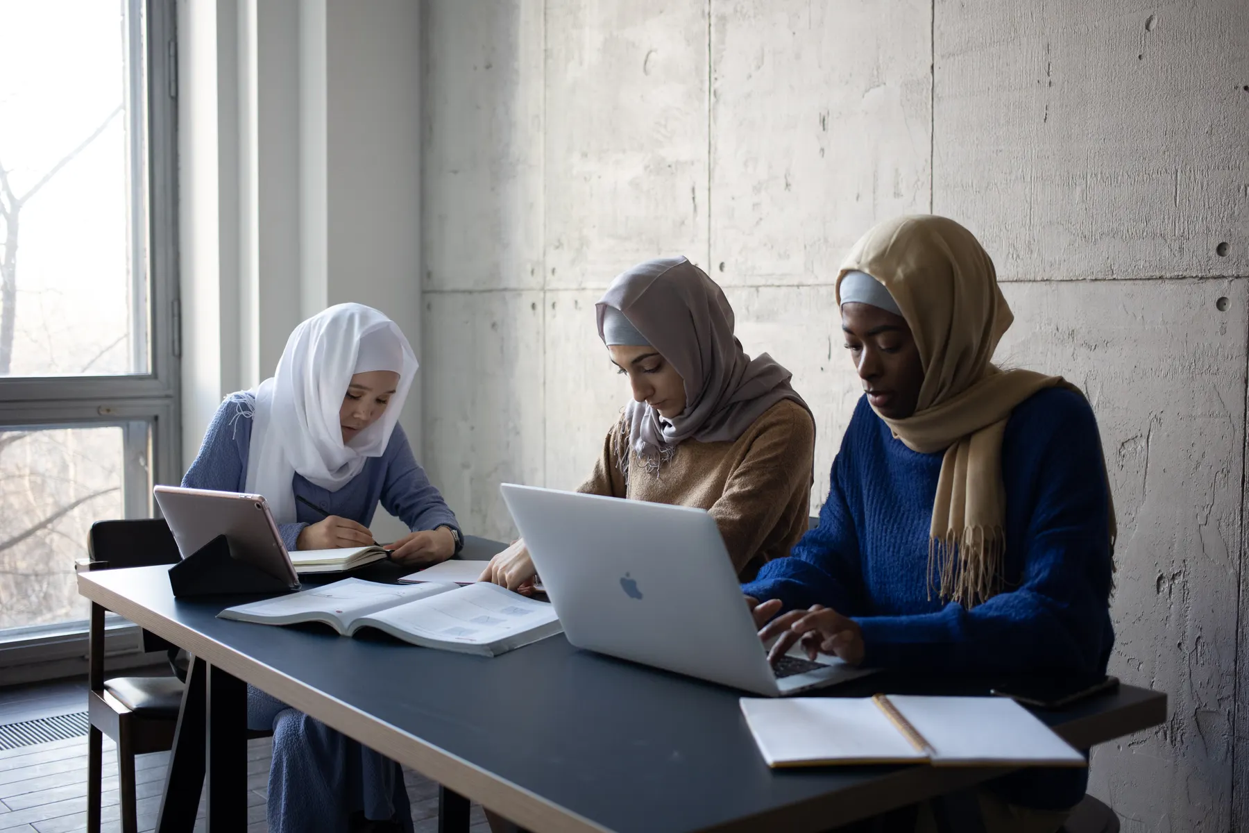 Ilustrasi tiga perempuan berhijab belajar bersama menggunakan laptop dan tablet